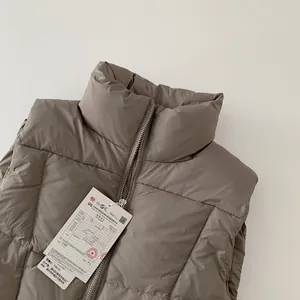 Dettaglio ravvicinato di un gilet imbottito per bambini color talpa con zip in metallo e collo alto