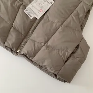 Dettaglio del gilet trapuntato marrone con cerniera e certificato di qualità