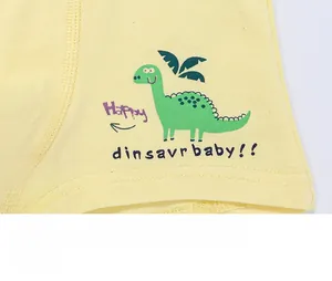 Detail of yellow cotton boys boxer briefs featuring cartoon dinosaur and printed text