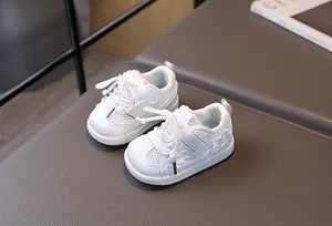 Close-up of baby mesh sneakers with pearl bow details and velcro closure on soft mat
