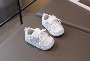 Detail view of white infant sneakers with breathable mesh, velcro strap, and pearl accents