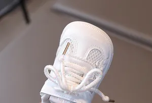 Detailed close-up of white baby sneaker showing breathable mesh and glittery laces