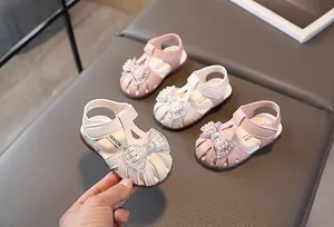 Close-up of girls hollow summer sandals with pearl bows and rhinestone accents