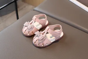 Close-up of pink toddler girl sandal with pearl rhinestone bow and velcro strap