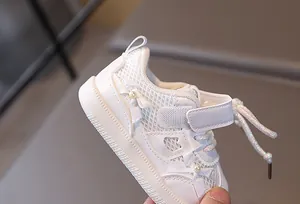 Detail of baby girl sneakers featuring breathable mesh, bow, pearls and velcro strap