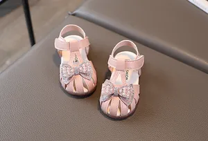 Close-up of pink leather sandals with a large bow, faux pearls and sparkling rhinestones