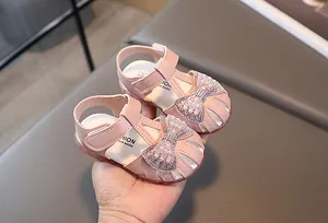 Detail of pink toddler sandals with rhinestone pearl bow and hollow closed-toe design