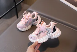 Detail of pink and blue kids sneakers with mesh upper and velcro strap held by hand