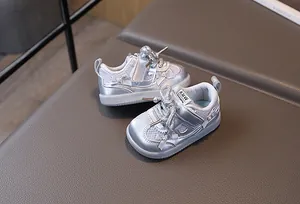 Detail of silver metallic baby sneakers with glitter laces, bow, and pearl accents