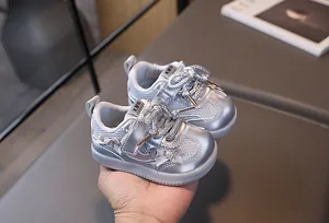 Detail of silver baby walking shoes featuring pearly bow accents and breathable mesh texture