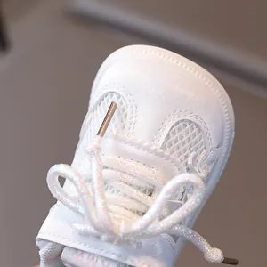 White baby walking shoes with sparkling laces and breathable mesh in a detailed view