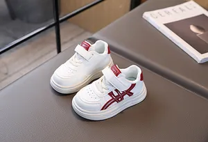 Detail of kids white casual sneakers with red cross stripes and velcro strap closure