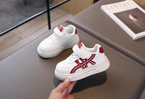 Side view of white and red kids sneakers with Velcro straps and breathable toe box