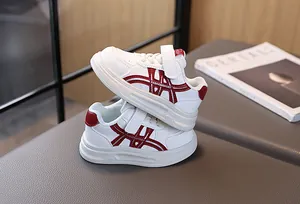 Detail of white kids sneakers with red stripes, hook-and-loop closure and thick soles