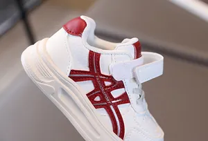 Detail of white kids sneakers featuring red accents and convenient Velcro straps