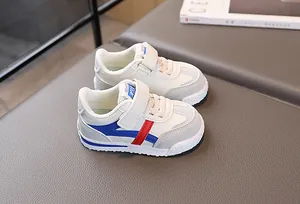 Dettaglio scarpe sportive bianche per bambini con inserti blu su tappeto grigio