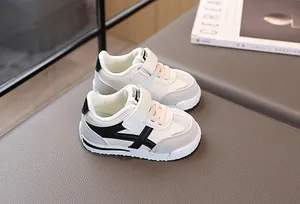 Dettaglio delle sneakers per bambini con pannelli in pelle nera, bianca e grigia e velcro