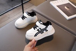 Detailed close-up of kids' white sneakers with black trim and velcro closure straps