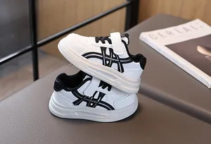 Detail of kids white sneaker with black stripes, hook and loop closure and non-slip sole