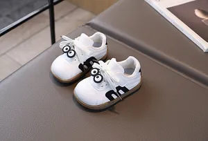 Detailansicht weißer Kleinkind-Sneaker mit süßen Comic-Augen und schwarzem M-Akzent
