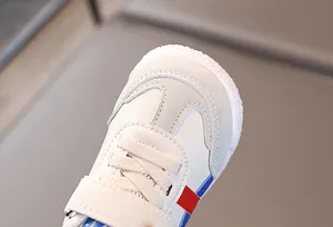 Dettaglio di scarpe per bambini con pelle martellata bianca e chiusura a strappo