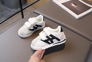 Detailed macro view of kids white sneakers with dual hook-and-loop straps and rubber sole