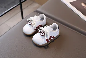 Detailansicht weißer Kleinkind-Sneaker mit Cartoon-Augen und roten M-förmigen Streifen
