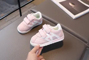 Detail of pink toddler sneakers with white stripes and double hook-and-loop straps