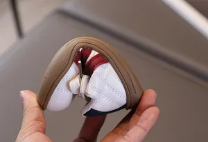 Detail der ultraflexiblen braunen Gummisohle von gestreiften Kindersportschuhen