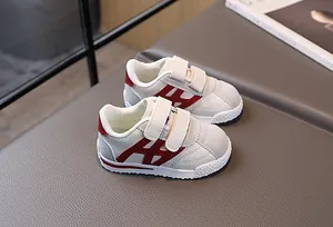 Detail of children's velcro sports shoes with red logo and breathable faux leather upper
