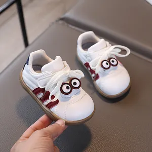 Elfenbeinfarbene Lauflernschuhe für Babys mit braunen Akzenten und Cartoon-Augen