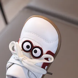 Weiße Lauflernschuhe für Babys mit roten Akzenten und 3D-Augen auf brauner Gummisohle