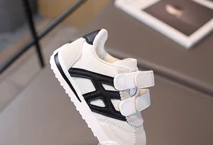 Detailed macro view of kids sneakers featuring white lychee grain leather and velcro straps