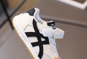 Vue détaillée du cuir blanc crème et des rayures noires sur cette basket de sport pour enfant