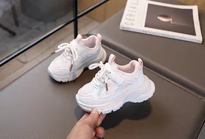 Détail de baskets enfant en maille avec touches roses et fermeture velcro sur un banc