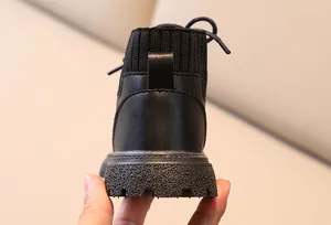 Close-up of black leather children's boots with knit collar and anti-slip rubber sole