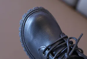 Dettaglio degli stivaletti martin in pelle nera per bambini con cuciture rinforzate