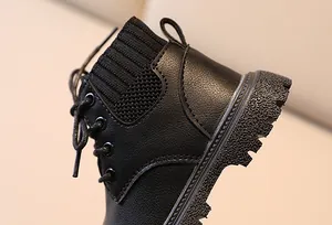 Close-up of children's black leather boots with knitted collar and thick anti-slip sole