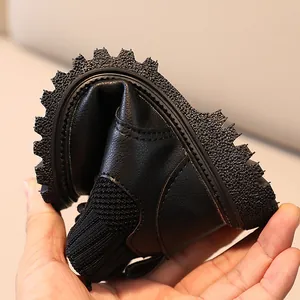 Flexible black leather kids boots with non-slip rubber soles showing easy bending feature