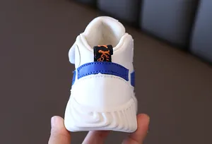 Rear view of white kids sneakers showing blue heel detail and orange pull tab
