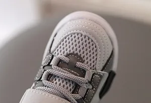 Detalle macro de zapatillas infantiles de malla transpirable con tejido de panal gris y puntera