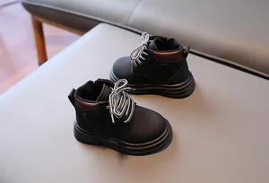 Détail de bottines noires mates pour enfants avec fermeture éclair et bordure métallique