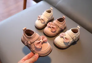 Détail de chaussures roses pour bambins avec nœud à carreaux rouges et col tricot
