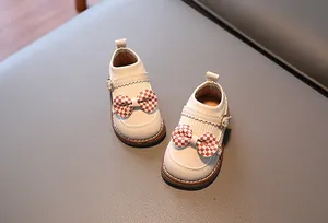 Détail de chaussures bébé fille en cuir blanc perle avec nœud à damier rouge
