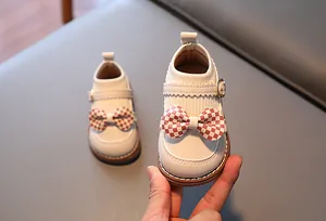 Détail de chaussures Mary Jane pour bébé avec nœud à carreaux rouges et cuir souple