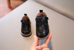 Dettaglio scarpe per bambini in pelle nera opaca con suola in gomma e chiusura a strappo