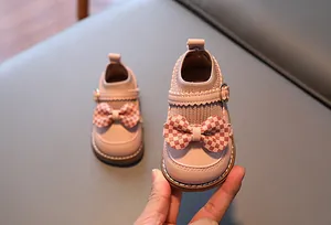 Détail de chaussures roses pour bébé avec nœud à carreaux et col en tricot élastique