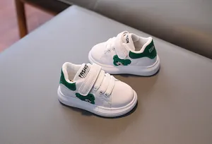 Detail of kids white and green sneakers with cute embroidered bear and velcro straps