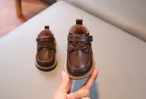 Dettaglio scarpe in pelle marrone per bambini con chiusura a strappo e suola