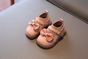 Vue détaillée des chaussures bébé roses avec nœuds à carreaux rouges et col en maille